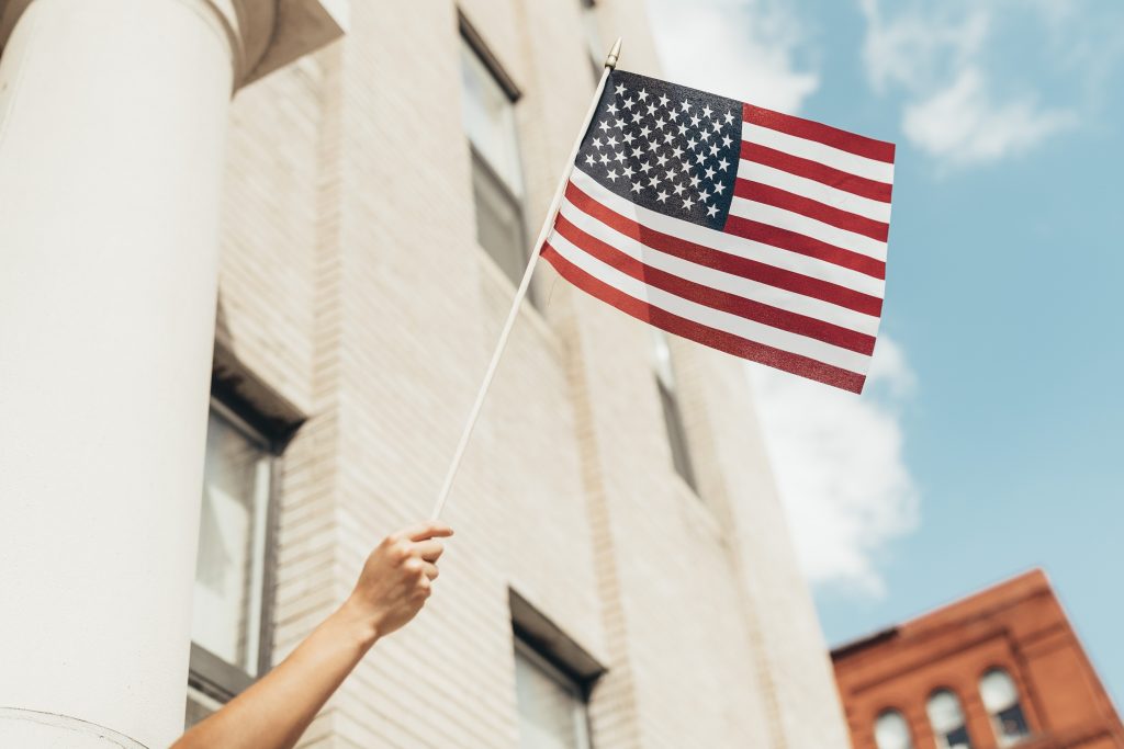 hand holding american flag against blue sky